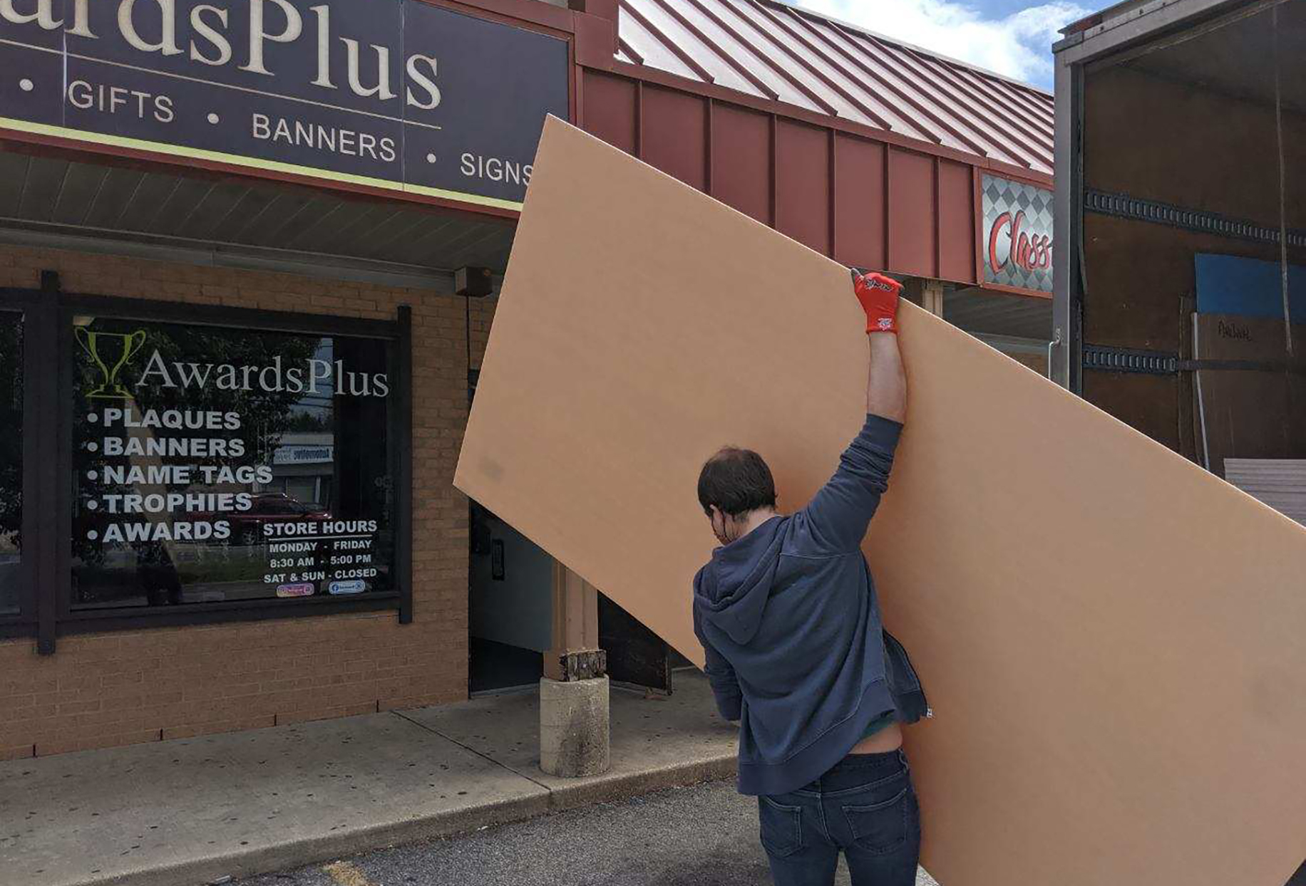 Man carries large acrylic sheet towards building